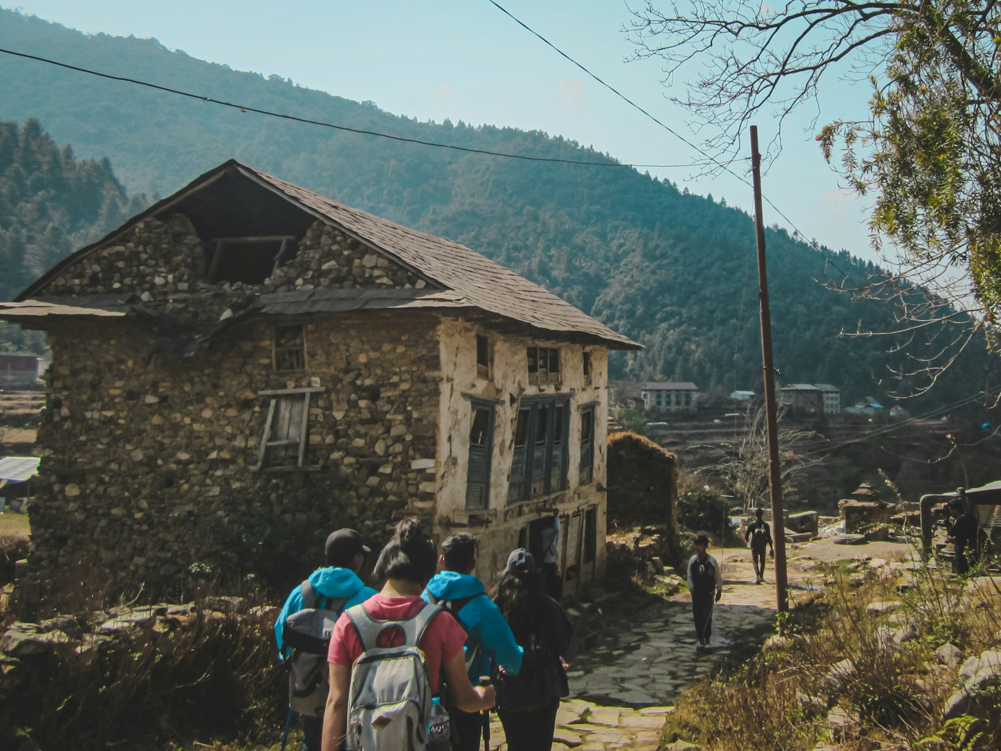 Hikers walk along a stone path through a mountain village.
